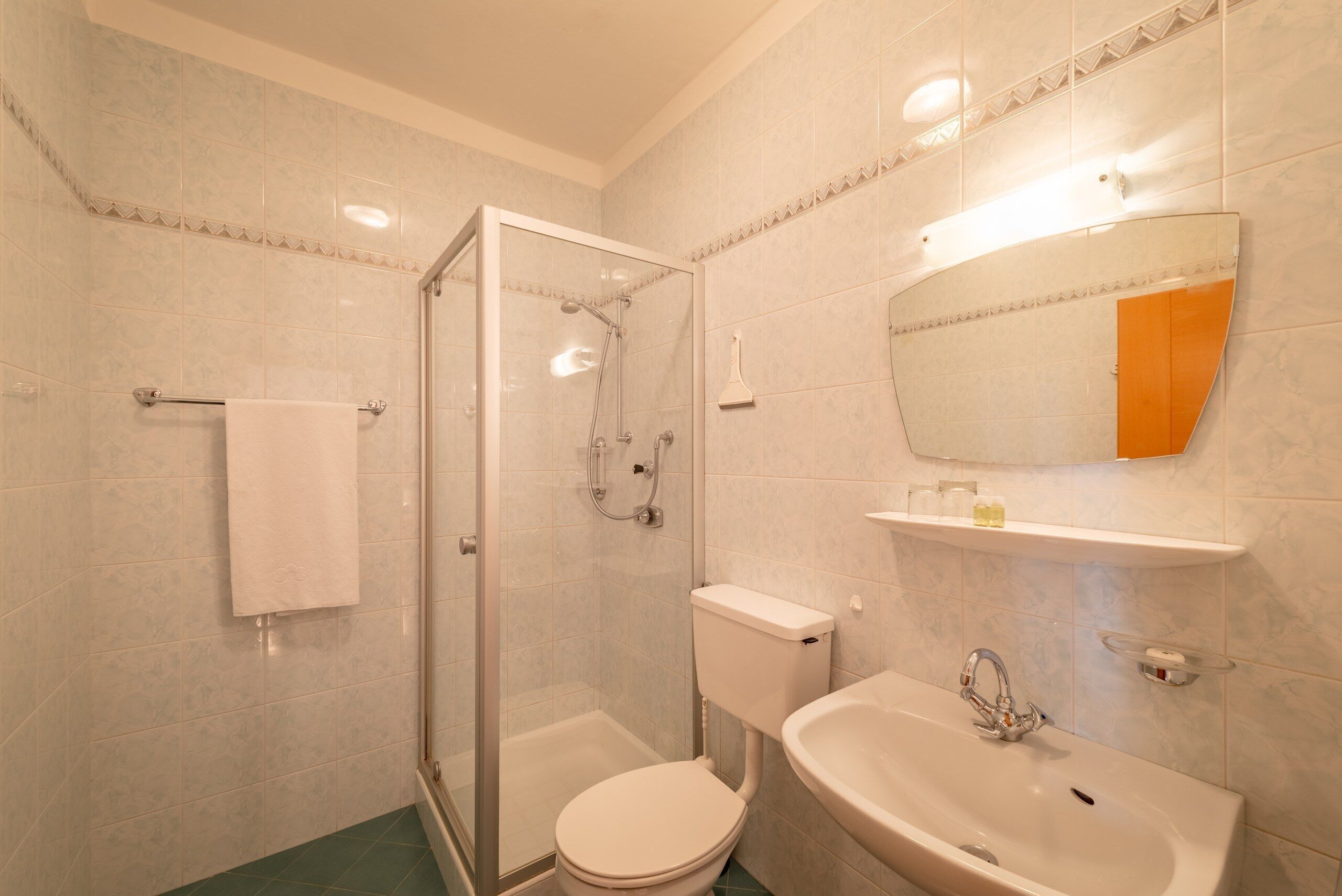 Une salle de bain avec une douche à parois de verre, des toilettes et un lavabo avec un miroir au-dessus.