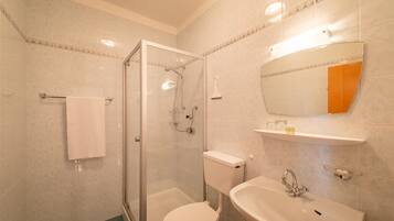 Une salle de bain avec une douche à parois de verre, des toilettes et un lavabo avec un miroir au-dessus.