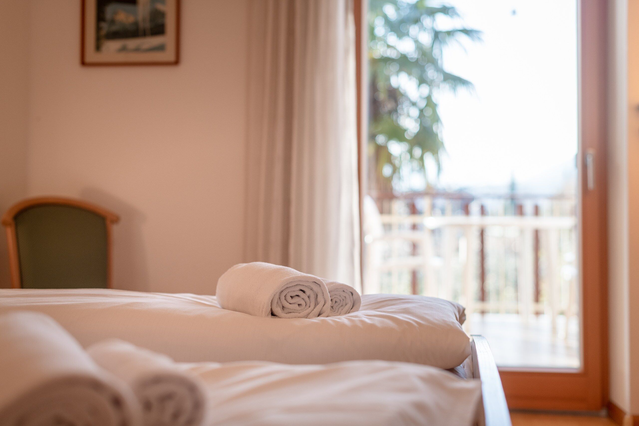 A hotel room with a bed, a chair, and a view of the outside.