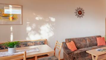 Un coin repas avec une table et des chaises en bois, un canapé avec des coussins et un luminaire suspendu.