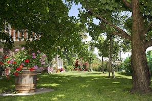Ein gepflegter Garten mit verschiedenen blühenden Pflanzen und einem Holzfass.