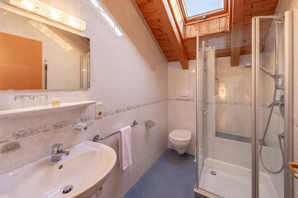 A modern bathroom with a shower, toilet, and sink.
