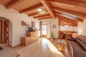 Amplia sala de estar con vigas de madera, un sofá, una mesa de centro y un televisor.