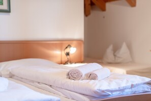 Un lit bien fait, avec des serviettes pliées, une lampe de chevet et des oreillers.