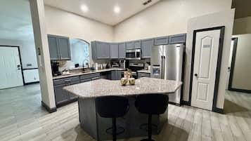 A modern kitchen with granite countertops, stainless steel appliances, and a central island with bar stools.