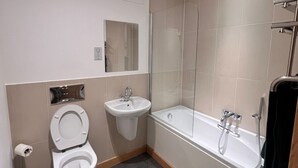 Une salle de bain moderne équipée de toilettes, d’un lavabo et d’une baignoire.