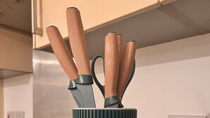 Un comptoir de cuisine sur lequel se trouve une tasse vert foncé à côtes, contenant des couteaux dont les manches sont en bois.