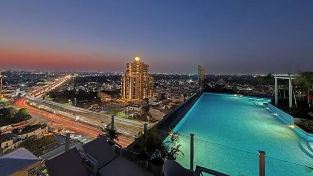 A rooftop pool with a city view at dusk.