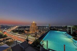 Una piscina en la azotea con vista a la ciudad al anochecer.