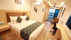 A hotel room with a bed, a desk, a chair, and a large window offering a view.