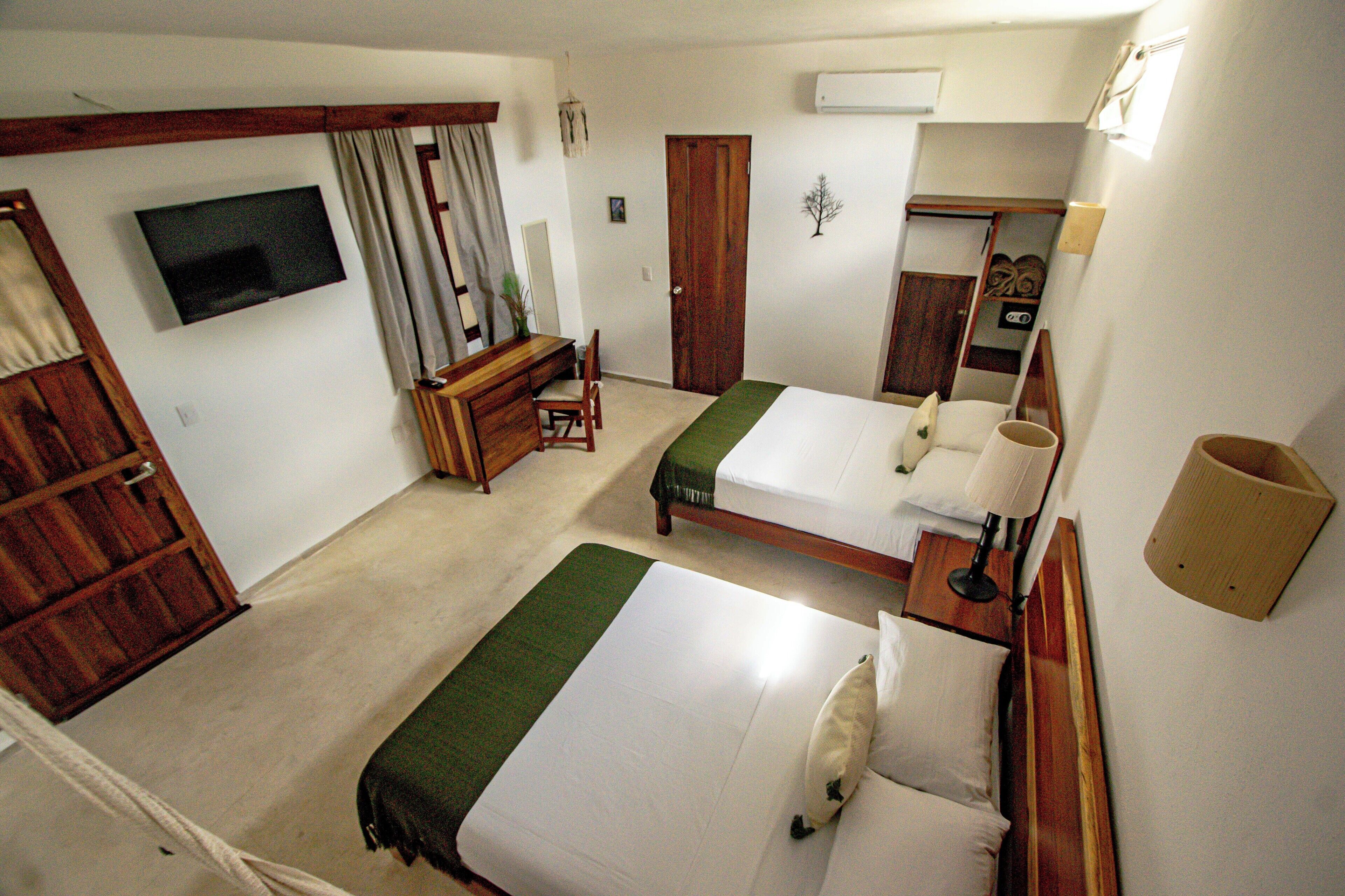 Habitación de hotel con dos camas, un escritorio, una silla, un televisor y un espejo.