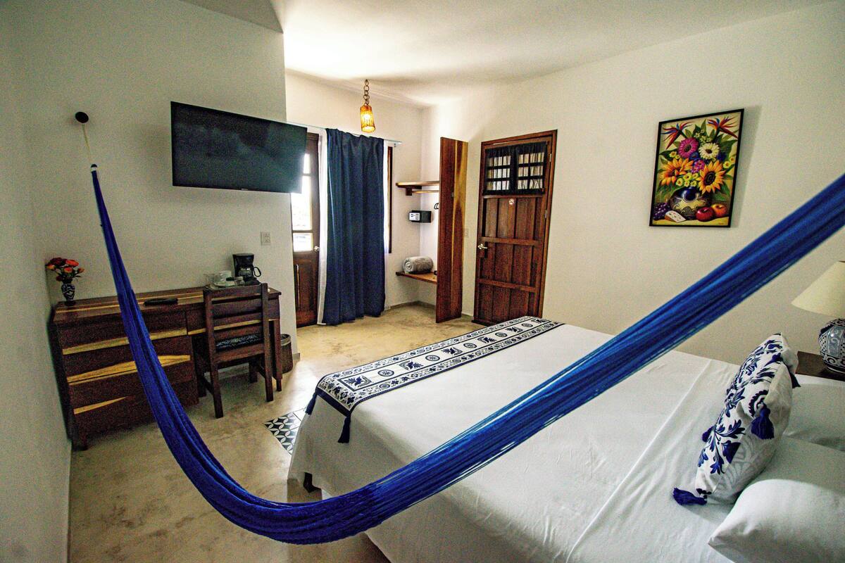 Un dormitorio con cama, escritorio, silla, televisor y puerta.