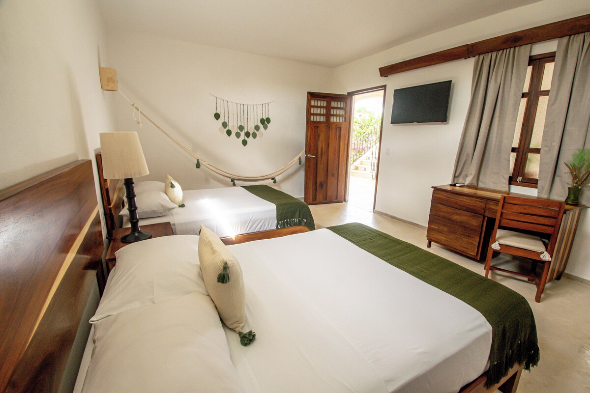 Een hotelkamer met twee bedden, een bureau, een stoel, een televisie en een deur naar buiten.