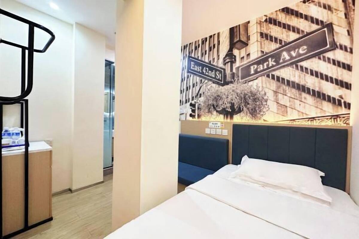Een hotelkamer met een bed, een bureau, een stoel en een muur met een verkeersbord.