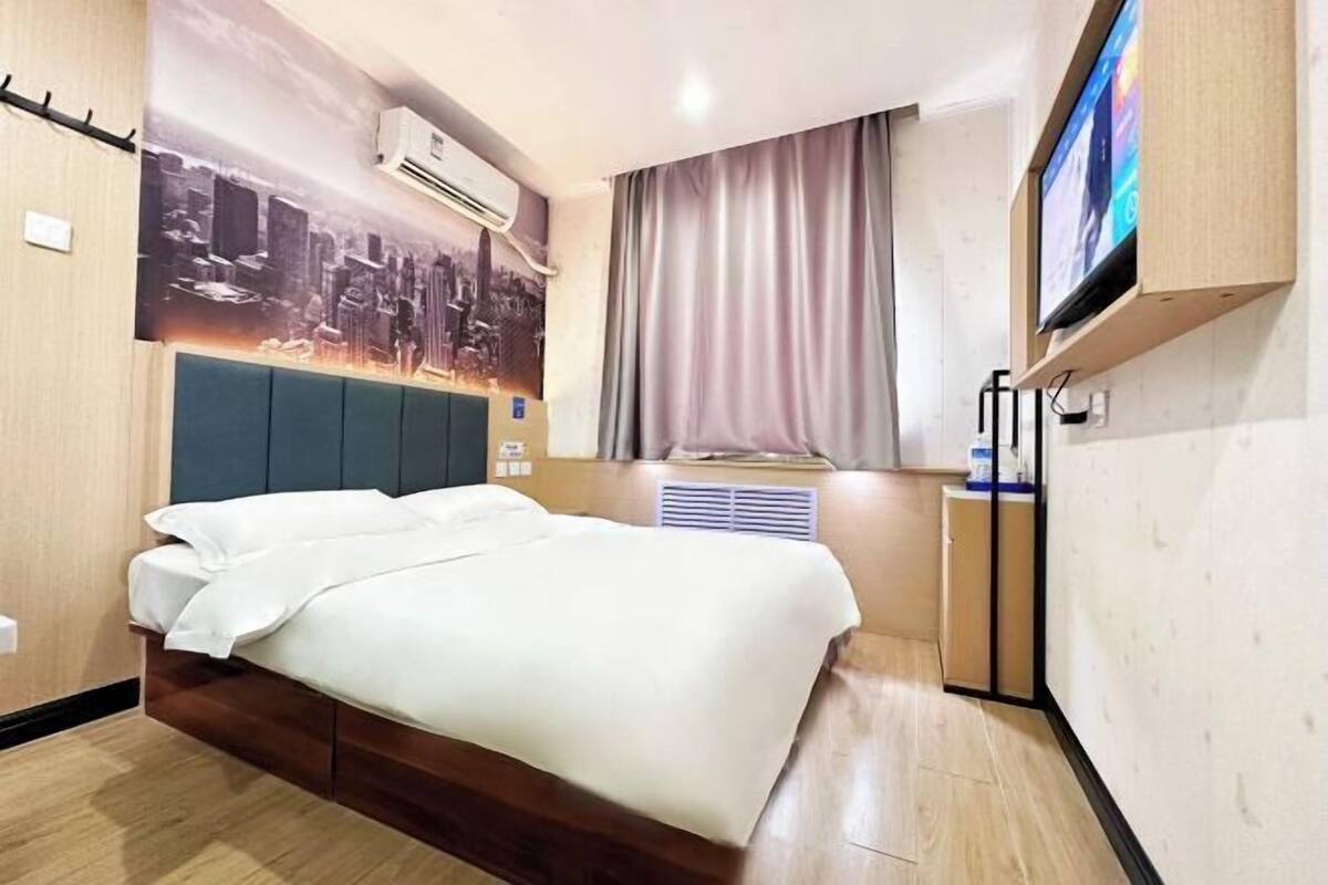 Hotelkamer met een bed, groot raam met gordijnen, airconditioning en een televisie aan de muur.