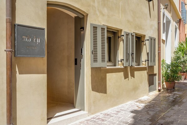 A building with a sign reading "TOU" and "SUITES" indicating a hotel. - Poem Suites (Chania)
