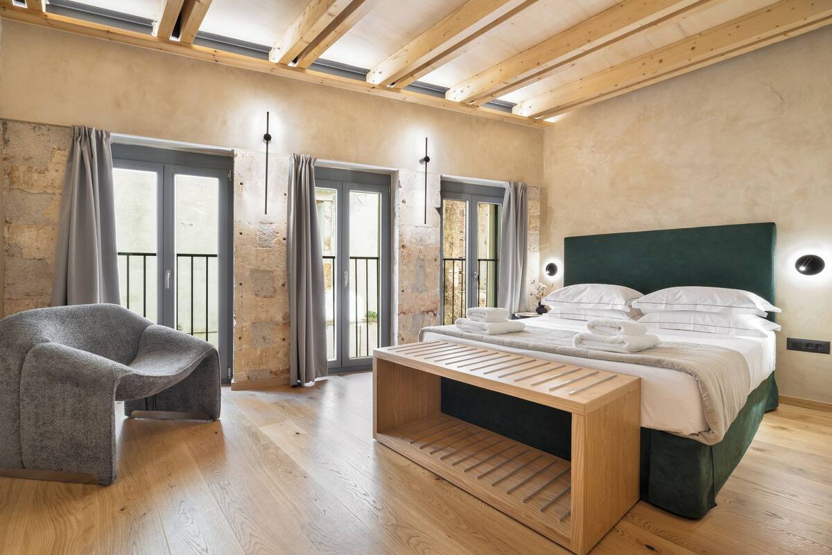 A modern bedroom with a bed, a chair, and a wooden bench.