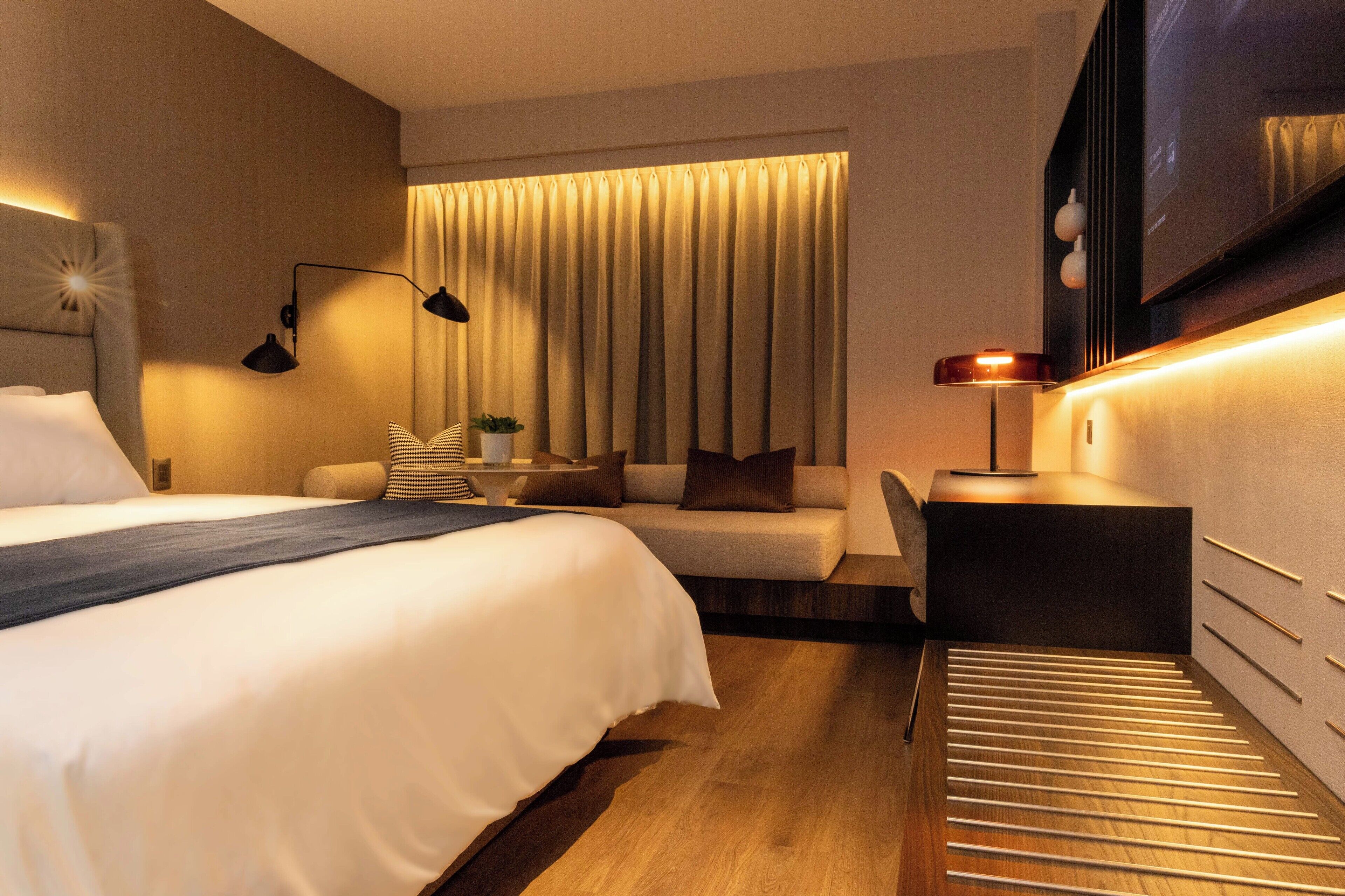Una habitación de hotel moderna con una cama grande, un sofá, un escritorio y un televisor.