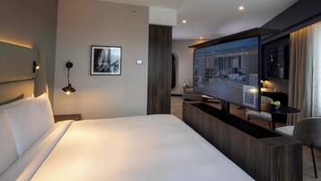 Habitación de hotel moderna con una cama grande, televisor, escritorio y zona de estar.