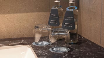 A bathroom counter with three bottles of complimentary water labeled 'Wyndham Grand Costa del Sol' and two empty glass jars.