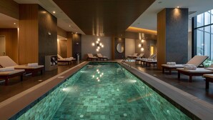 Una piscina interior moderna con zonas de descanso y un amplio ventanal.