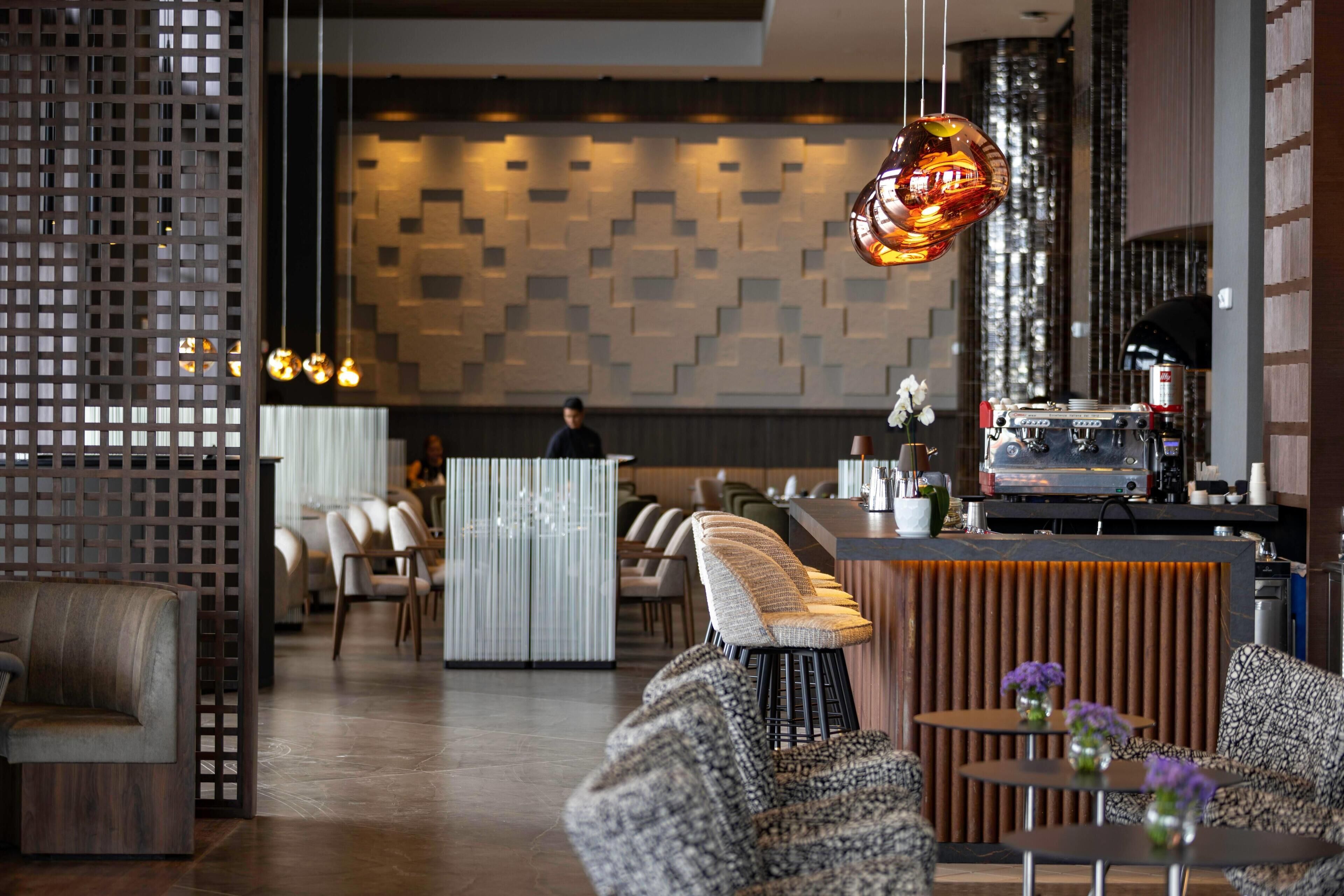 Un interior moderno con distribuciones de asientos, una zona de bar y una pared con diseño.