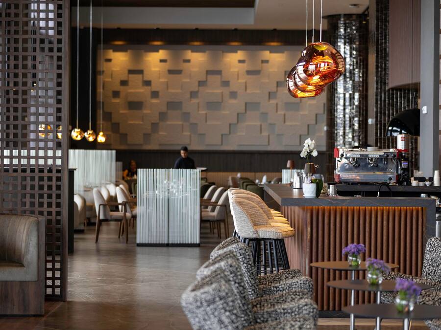 Um interior moderno com disposição de assentos, área de bar e parede estampada.