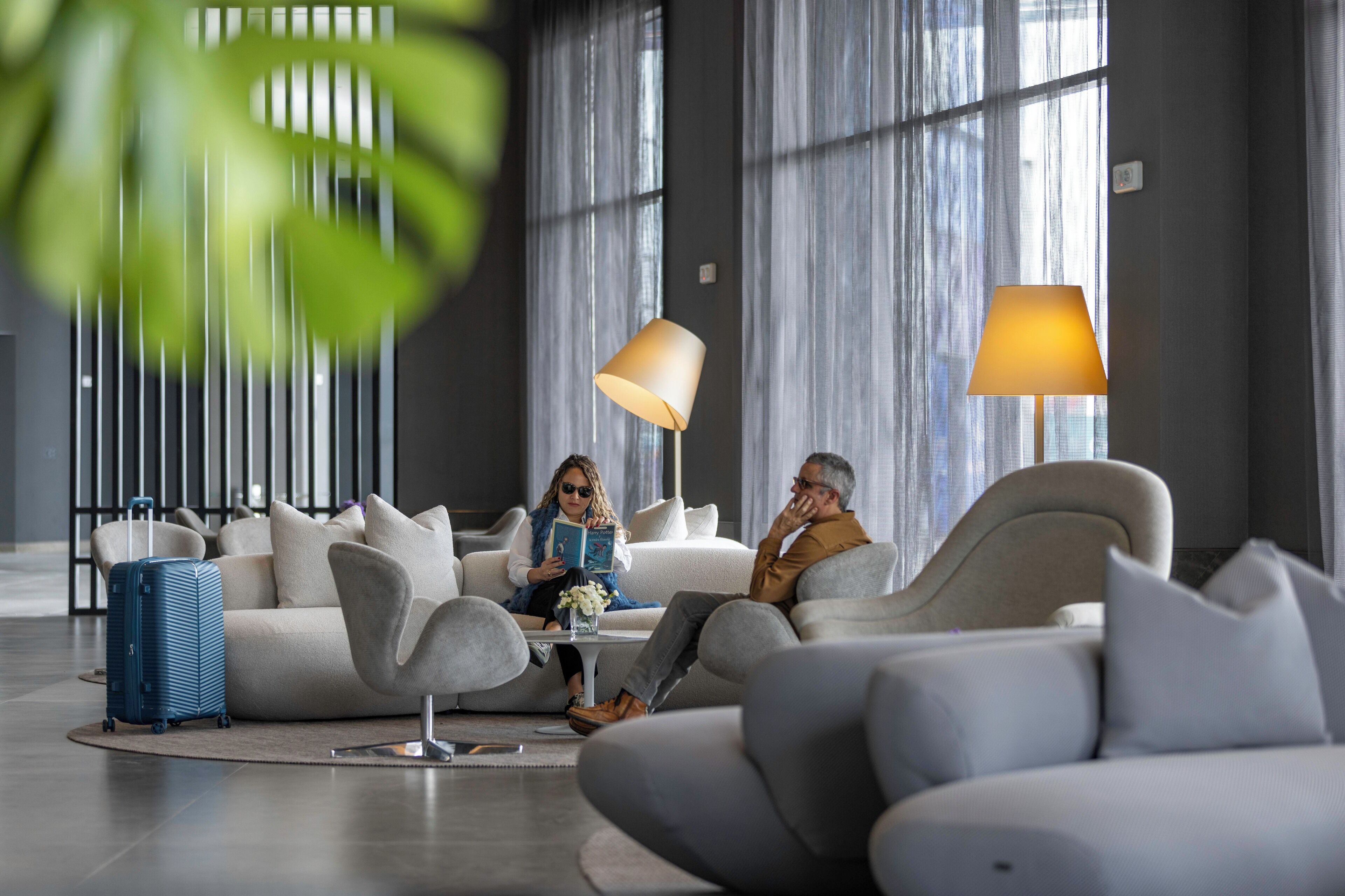 A modern living room with a sofa, two lamps, and a blue suitcase.