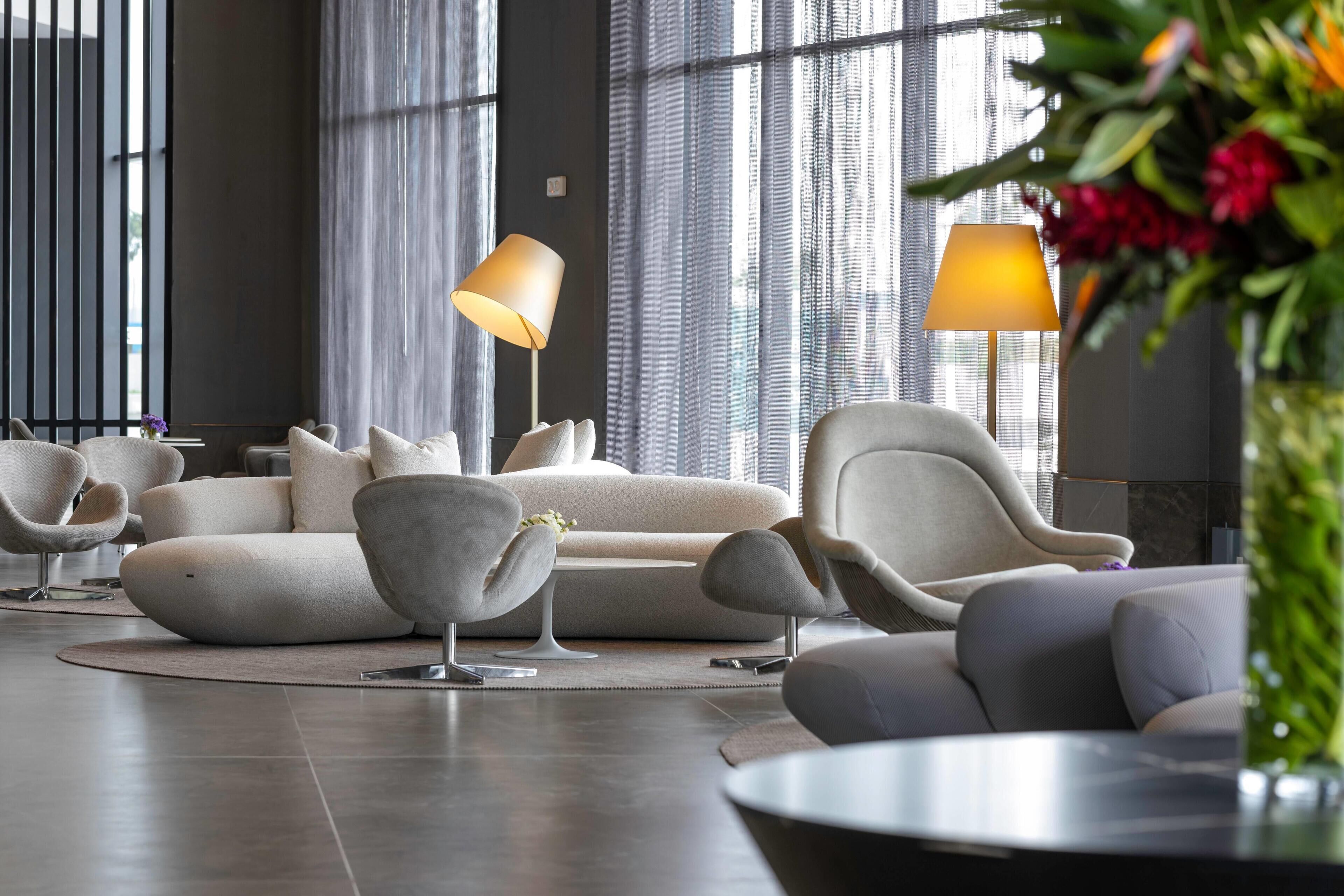 A modern living room with a sofa set, armchairs, and two floor lamps.