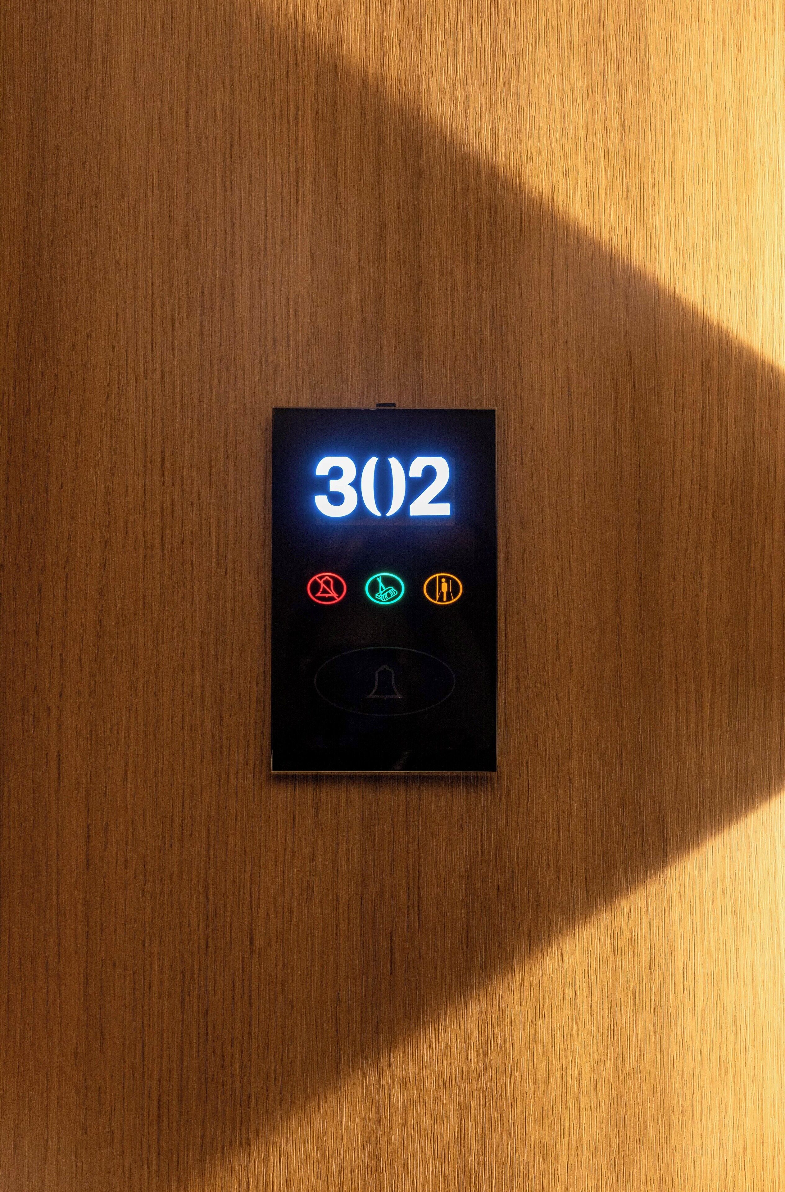 A digital display on a wooden surface with the number 302 and various icons.