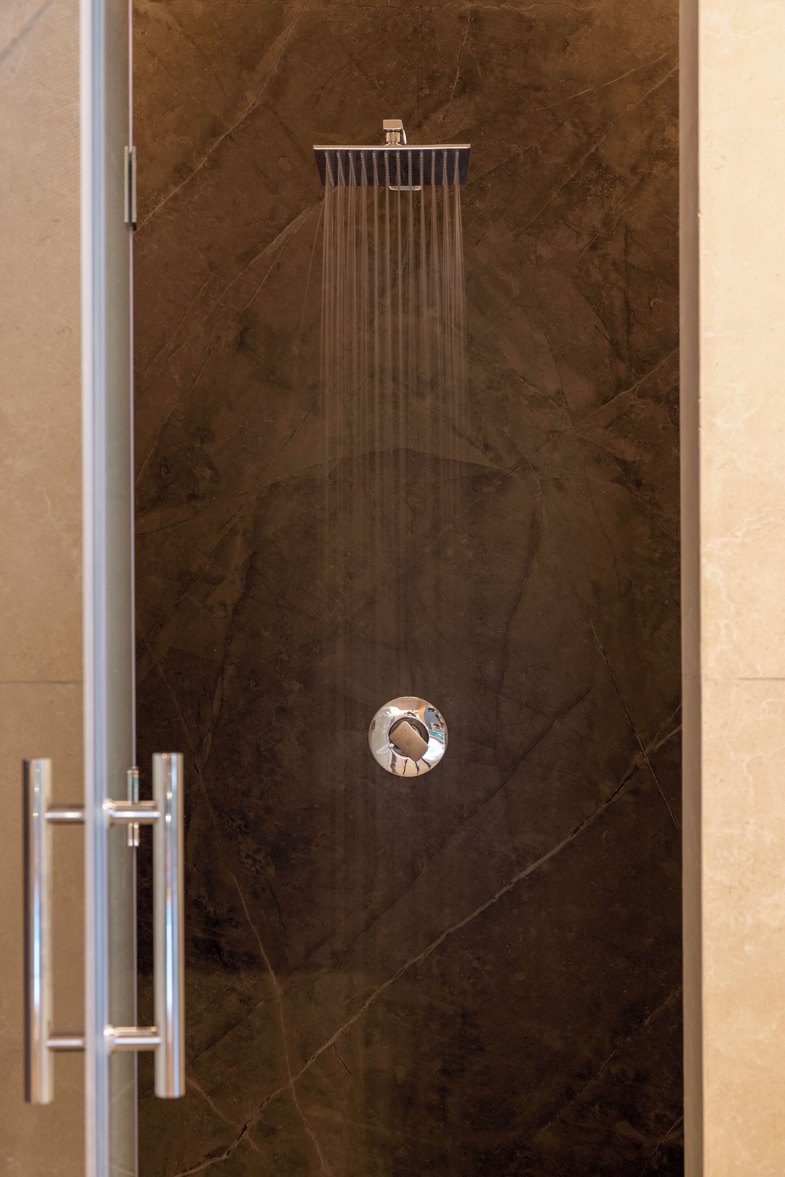 A shower with a modern design, featuring a wall-mounted control panel and a glass door.