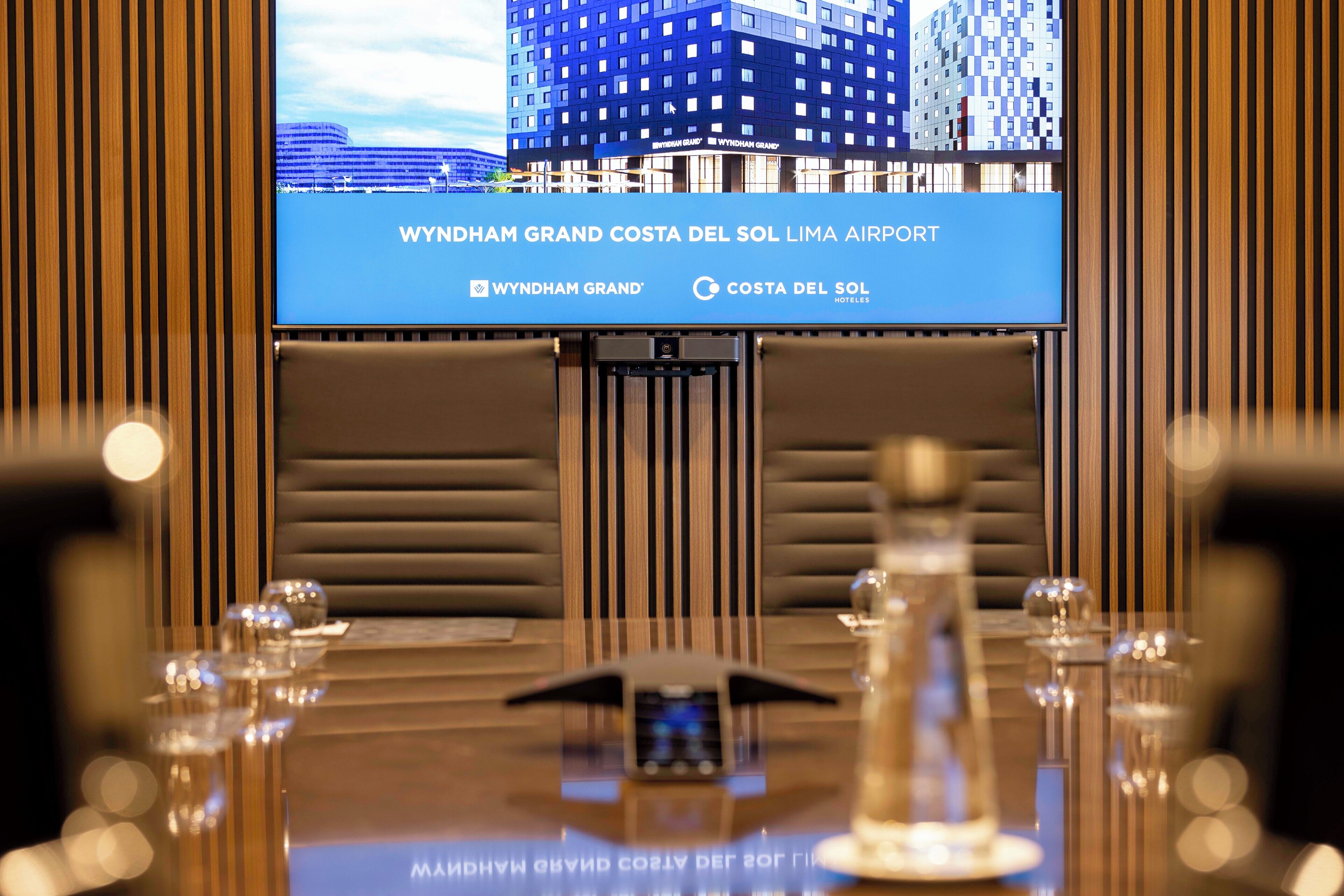 A conference room with a large screen displaying the Wyndham Grand Costa del Sol Lima Airport.