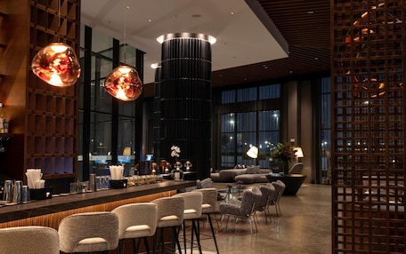 A modern bar area with a long counter, multiple bar stools, and a central decorative column.