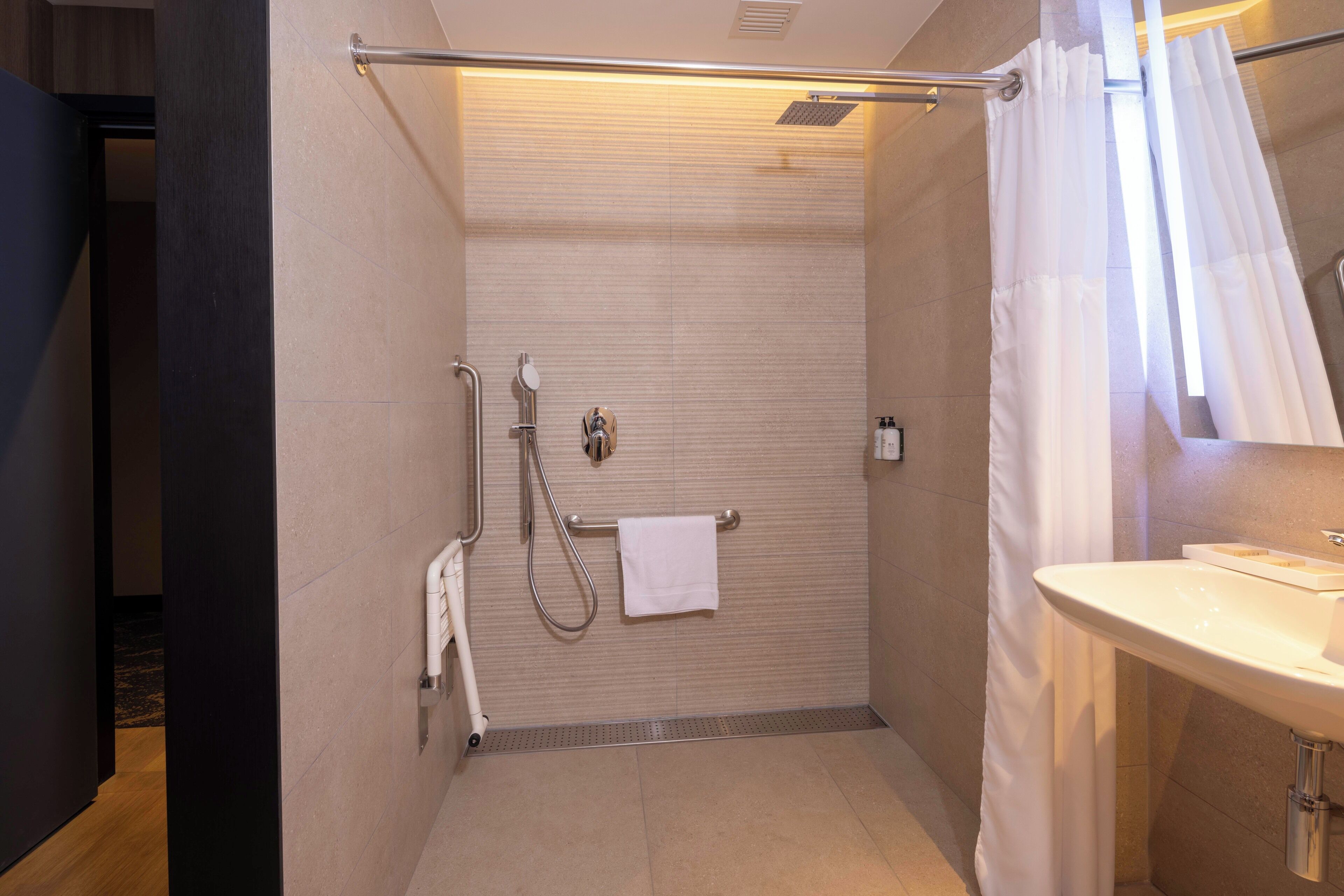 A modern bathroom with a shower, a towel rack, and a sink.