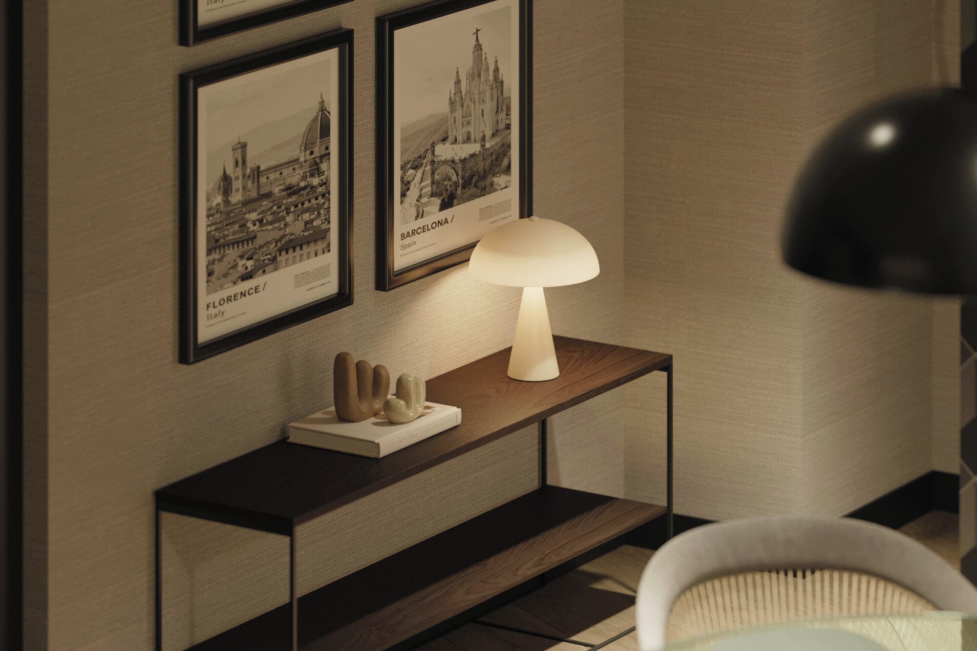 A room with a wooden console table displaying framed pictures of Florence and Barcelona, a white lamp, and a black floor lamp.