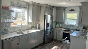 Una cocina moderna con gabinetes grises, electrodomésticos de acero inoxidable y un salpicadero de azulejos.