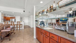 Un'ampia cucina con mobili in legno, un angolo bar con bicchieri e una macchina da caffè.