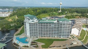Un grande hotel con diversi piani, una piscina e una torre sullo sfondo.
