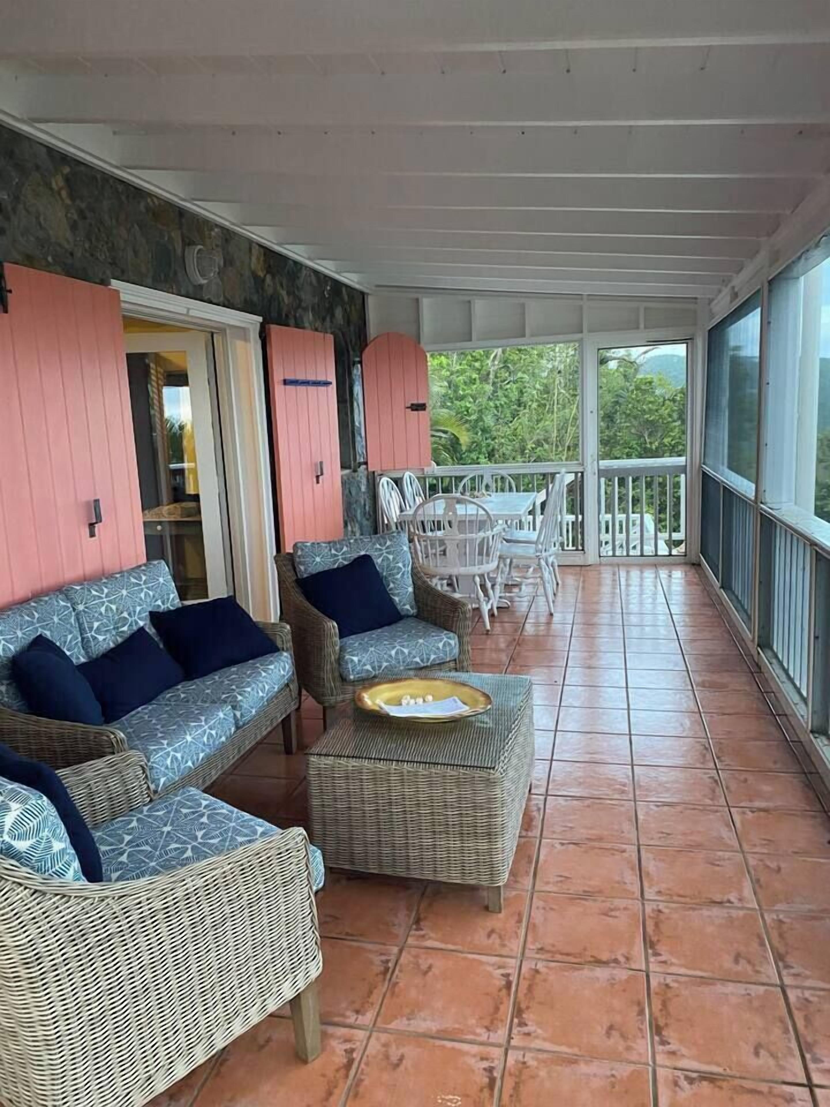 A covered outdoor seating area with wicker furniture and a tiled floor.