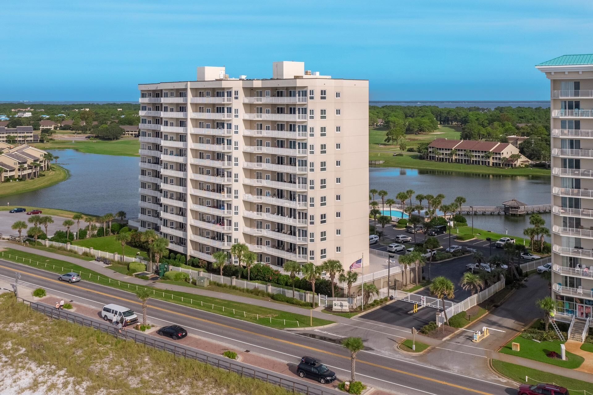 Ein Hochhaus mit mehreren Balkonen, einem Parkplatz und Blick auf See und Meer.