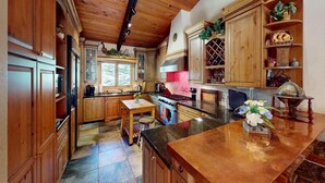 Une cuisine avec des meubles en bois, un fourneau et une fenêtre donnant sur une forêt.