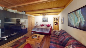 A cozy living room with a sofa, a coffee table, a TV, and a fireplace.