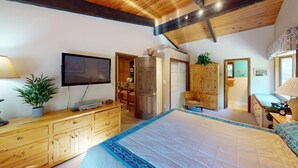 Une chambre avec un grand lit, des meubles en bois, une télévision et une plante.