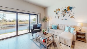 A modern living room with a large sliding glass door, a sofa set, a coffee table, and a world map mural on the wall.