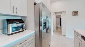 A modern kitchen with white cabinets, a stainless steel refrigerator, and a built-in oven.