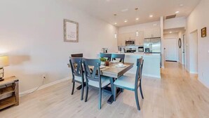 A modern kitchen with white cabinets, a central island, and a dining area with a table and chairs.