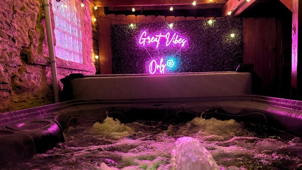A hot tub with a neon sign reading "Great Vibes" in a dimly lit room with stone walls and string lights. - House of Fun-Large Family Home W/HotTub & Games (Pittsburgh)