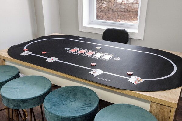 A craps table with chips and cards, surrounded by four blue stools.