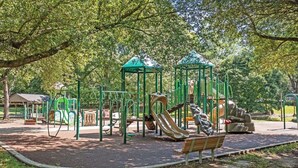 Une aire de jeux avec des structures d’escalade, des toboggans et un banc.