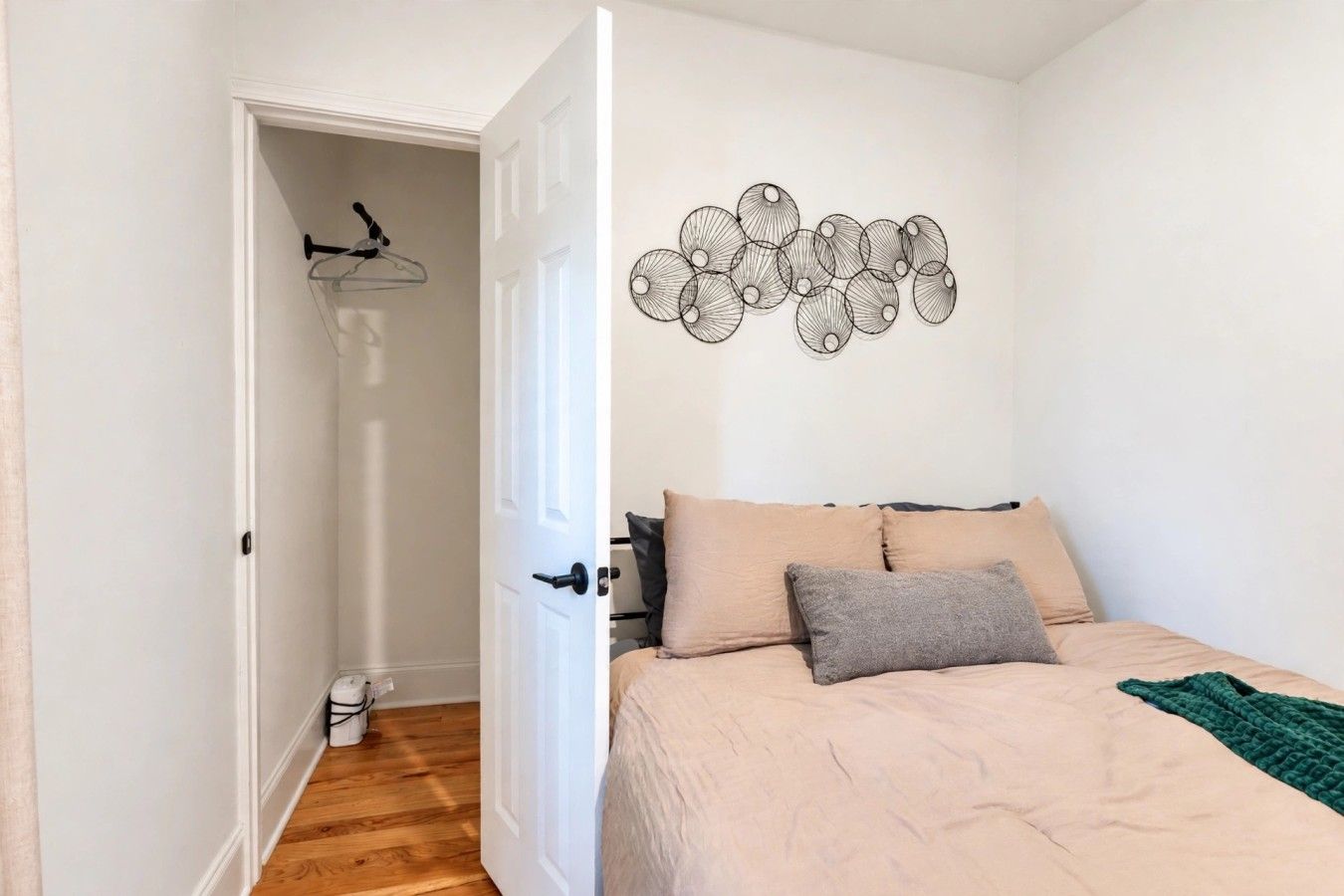 Une chambre avec un lit, une œuvre d’art murale et une porte donnant sur un couloir.